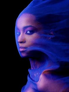 a woman's face is covered in blue fabric as she poses for the camera