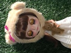 a doll is laying on the grass next to a teddy bear wearing a white dress