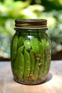 a jar filled with green beans sitting on top of a wooden table