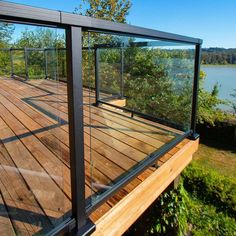 a wooden deck next to a lake with glass railings