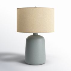 a blue table lamp with a beige shade on it's base and a white background