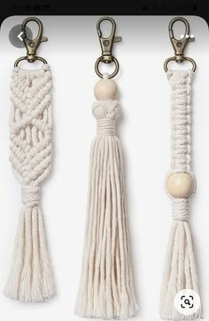 three white tasselled key chains with wooden bead ends and two brass hooks