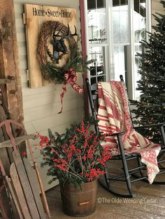 a rocking chair sitting on the porch next to a christmas tree and potted plant