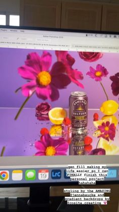 a computer screen with flowers on it and a can of beer in front of the monitor