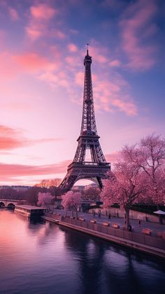 the eiffel tower is lit up in pinks and purples as the sun sets