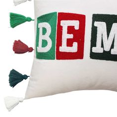 a white pillow with the word bem on it and tassels around it