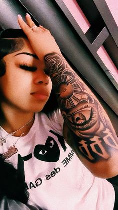 a woman with tattoos on her arm leaning against a wall