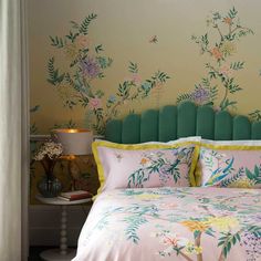 a bed with green headboard and floral wallpaper on the walls behind it in a bedroom