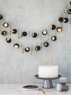 a white cake sitting on top of a table next to a black and gold garland