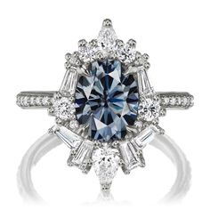 a blue and white diamond ring with three baguets on the side, surrounded by diamonds