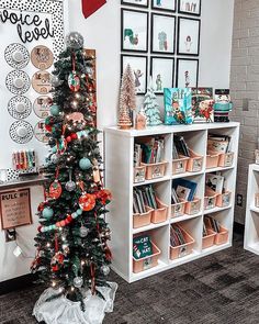 a decorated christmas tree sitting in front of a white book shelf filled with lots of books