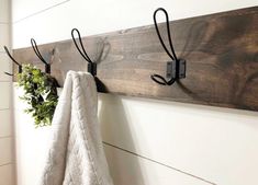 a towel hanging on the wall next to a coat rack with two hooks and a potted plant