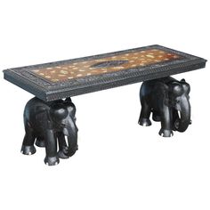 an elephant bench with two elephants on it's legs and a table top in the middle