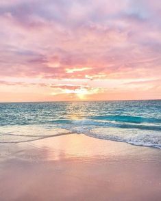 the sun is setting over the ocean with waves coming in to shore and pink clouds