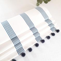 four white and blue striped napkins with black pom - poms on them