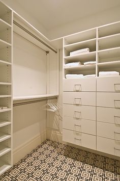 an organized closet with white drawers and shelving units on the wall, in front of a patterned floor