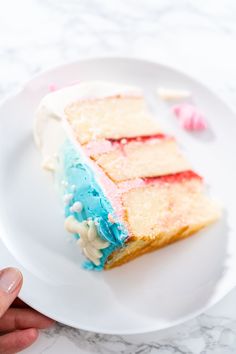 a piece of cake with blue, white and red frosting on a plate next to a hand