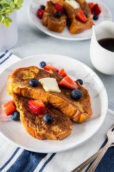 two white plates topped with french toast and fruit