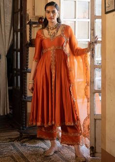 Featuring a rust chiniya silk anarkali set paired with tissue base dupatta with antique gold zari resham embroidery. Elegant Anarkali Suits, Ethnic Anarkali Dresses, Tissue Anarkali Dress, Embroidery On Orange Fabric, Tissue Fabric Dress Design, Silk Dresses Indian, Rust Orange Lehenga, Wedding Guests Outfits, Elia Martell