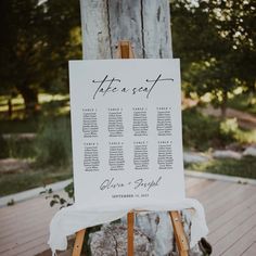 a wooden easer with seating cards on it sitting in front of a large tree