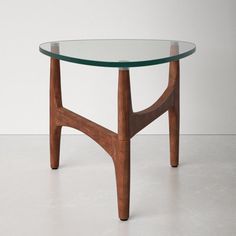 a table with a glass top and wooden frame on the bottom, against a white wall