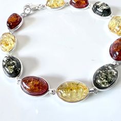 Elegant Classic Amber Bracelet An elegant classic sterling silver with oval multicolor amber bracelet. This bracelet has 11 natural amber oval beads set in sterling silver. ATTN. Please note since Amber is natural all pieces might slightly vary in color from the image. Bracelet Size: about 8 inches. Amber color: honey ( dark brown), green, lemon Amber size: each stone about ½ x ⅓ inch ( oval shape ) Weight: 9.4 g Material: .925 sterling silver, natural Baltic amber. Made in Poland. Oval Sterling Silver Bracelet With Natural Stones, Multicolor Oval Bracelets With Natural Stones, Elegant Oval Amber Bracelets, Green Lemon, Amber Bracelet, Oval Beads, Natural Amber, Amber Beads, Amber Jewelry