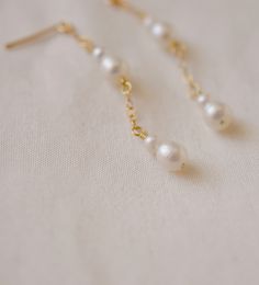 A whisper of pearls. These delicate droplet earrings are handcrafted with natural white freshwater pearls suspended from a shimmering chain of sterling silver or 14k gold filled. Elegant and timeless, these earrings will grace any special occasion, wedding, or everyday look. EARRING LENGTH: 1.5" (38mm) Delicate Long Drop Pearl Earrings In 14k Gold, Delicate Pearl Chain Earrings In 14k Gold, White Long Drop Pearl Earrings In 14k Gold Filled, Delicate Pearl Drop Linear Earrings, White Long Drop Pearl Earrings In 14k Gold, Delicate White Linear Earrings With Pearl Charm, Delicate Akoya Pearl Earrings, Dainty Pearl White 14k Gold Filled Pearl Earrings, White 14k Gold Earrings With Pearl Chain