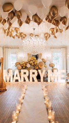 a large room with many balloons and candles on the floor, along with a sign that says marry me