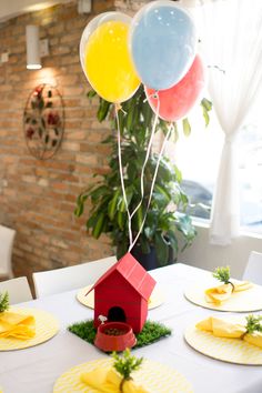 a table topped with plates covered in cake next to a red birdhouse and balloons