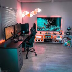 a computer desk with two monitors and a laptop on it in front of a television