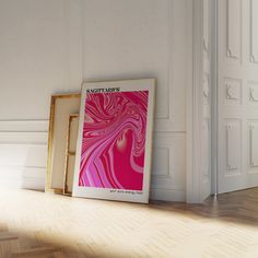 an empty frame sitting on the floor next to a pink poster