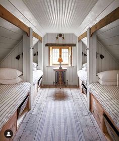 there are three beds in the room with white walls and wood beams on the ceiling