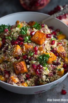 a white bowl filled with food and garnished with parsley next to pomegranates