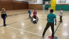 a group of people standing on top of a wooden floor in a gym next to each other