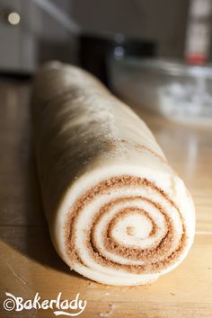 a rolled up cinnamon roll sitting on top of a wooden table