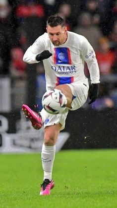 a man kicking a soccer ball on top of a field