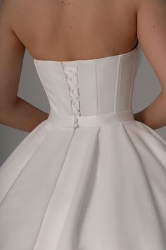 the back of a woman's white wedding dress, with buttons on the waist