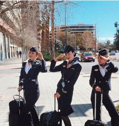 three women in air force uniforms standing on the sidewalk with luggage and salutes their hats