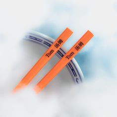 two orange chopsticks sitting on top of a white and blue plate in the clouds