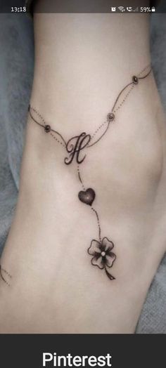 a woman's foot with a flower and heart tattoo on the bottom of it