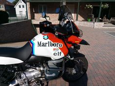 an orange and white motorcycle parked on top of a brick road next to a building