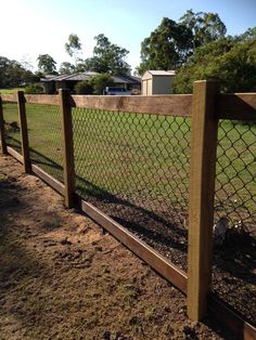 a fence that is next to a field with grass and dirt on the ground in front of it