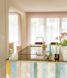 a kitchen with marble counter tops and colorful striped wallpaper on the walls, along with flowers in vases