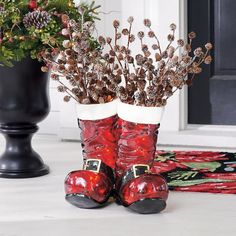 two red boots sitting next to each other in front of a black potted plant