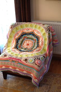 a crocheted blanket sitting on top of a wooden bench next to a window