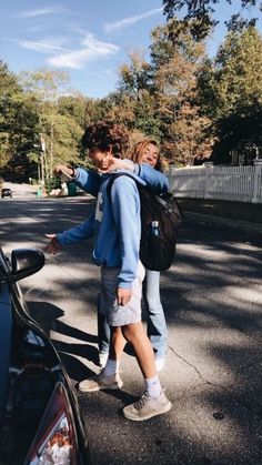 two people standing next to each other near a car