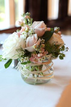 a vase filled with white and pink flowers on top of a table next to a window