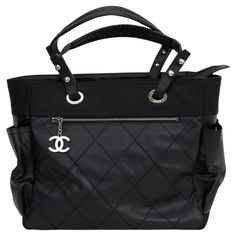 This is Chanel Coated Canvas Quilted Paris Biarritz Tote in black. This super chic tote features quilted coated canvas. The bag features tall top handles, side pockets, a front zipper pocket with a chanel CC zipper pull, and silver hardware. The top zips open to a black fabric interior with zipper, patch pockets, and a removable pouch. Comes with hologram and original dust cover. Chanel Coat, Vintage Chanel Bag, Chanel Suit, Chanel Tote, Leather Frames, Chanel Vintage, Shopper Tote, Black Quilt, Gucci Black