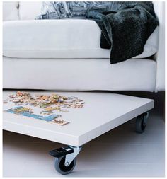 a living room with a white couch and a coffee table on casteors in front of it