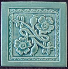 a ceramic tile with flowers and vines on it